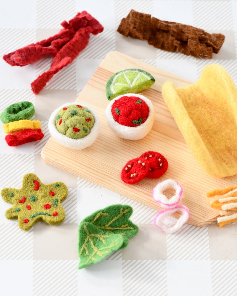 US stockist of Tara Treasures. Felt taco set with toppings on a wooden board against a checkered background