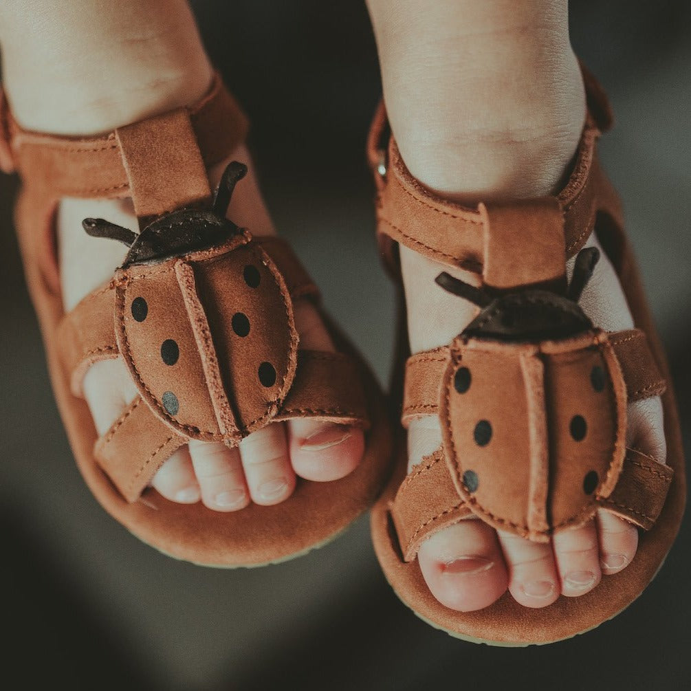 US stockist of Donsje USA's Lady Bird Tuti Sky  premium handmade leather sandals.  Red in color with beautiful lady bird on front and velcro fastening at back.  Sizes 0-12 mths have soft sole, 12-30mths have a soft flexible, rubber sole.