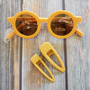 US stockist of Grech & Co's gender neutral sustainable sunglasses.  Made from recycled plastic, with round amber lens with UV 400 protection in a golden color.