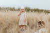 US stockist of Grown Clothing's Flower Field dress made from organic cotton.  Features gathered skirt, ties at shoulder and had machine embroidered gold flowers on the bib.  Oatmeal in color.