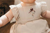 US stockist of Bencer & Hazelnut's Christmas Fir Playsuit.  Made from oatmeal colored cotton fabric, with ruffles on the back and embroidery on the front.  Snaps at crotch.