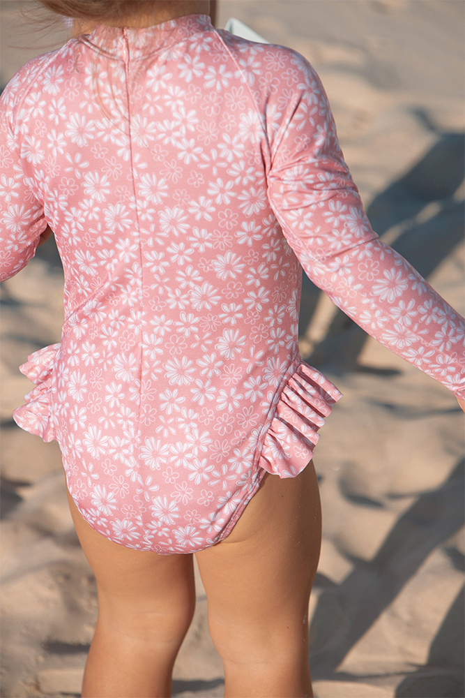 US stockist of Salty Swimwear's Zoe long sleeve rashsuit in pink daisy days.  Made from pink UPF 50+ recycled Repreve fabric with pretty white daisy print. Fully lined, with invisible back zipper and signature Salty frill on legs.