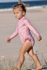 US stockist of Salty Swimwear's Zoe long sleeve rashsuit in pink daisy days.  Made from pink UPF 50+ recycled Repreve fabric with pretty white daisy print. Fully lined, with invisible back zipper and signature Salty frill on legs.