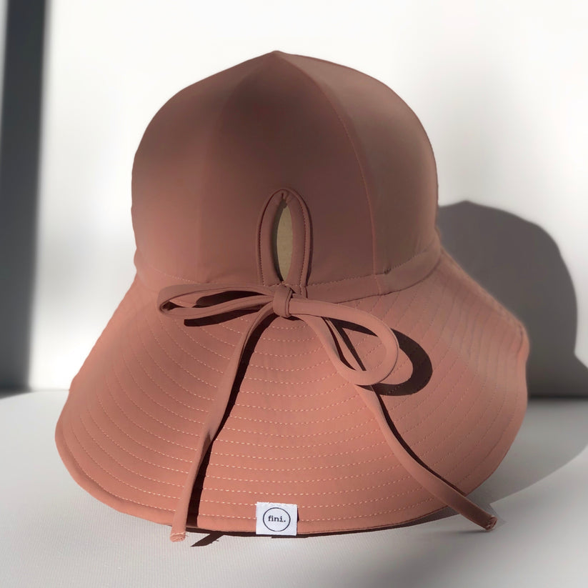 US stockist of Fini the Label's gender neutral, floppy swim hat in cocoa. Features elongated back for added sun protection, chin strap and adjustable bow around crown for better fit. Brim is medium stiffness and can be flipped up at front.  Made from nylon/spandex and is quick drying.