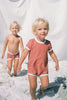 The US stockist of Zulu & Zephyr Mini Rib Onesie in Plum.  A loose fit gender neutral style made from sustainable ECONYL UPF 50+ fabric.  Short sleeved with contrasing back zipper and binds.  Fully lined.