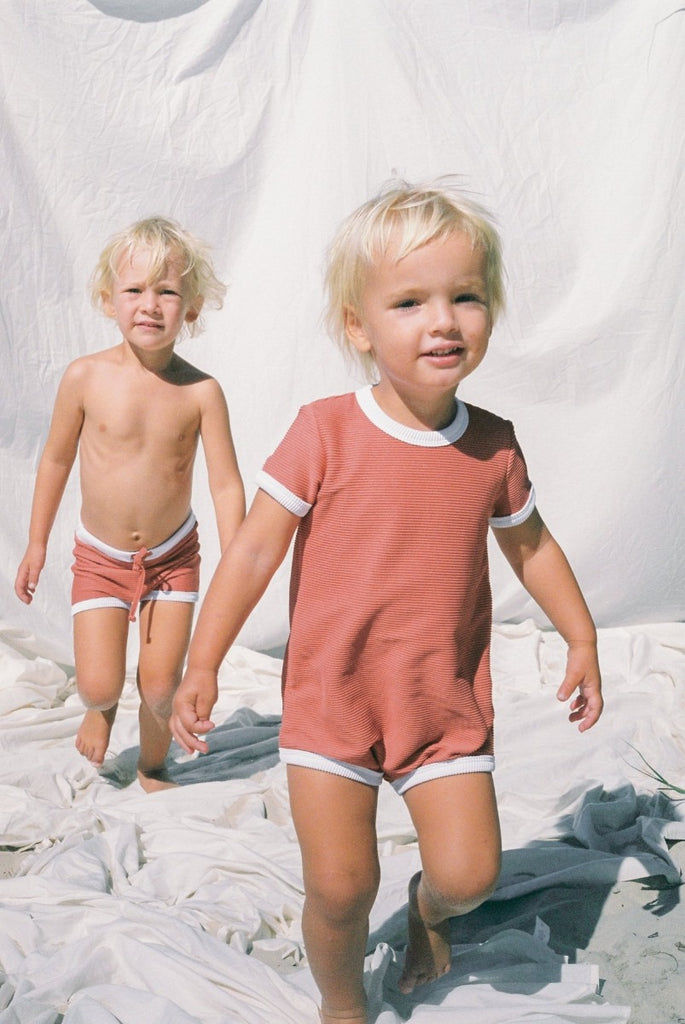 The US stockist of Zulu & Zephyr Mini Rib Onesie in Plum.  A loose fit gender neutral style made from sustainable ECONYL UPF 50+ fabric.  Short sleeved with contrasing back zipper and binds.  Fully lined.