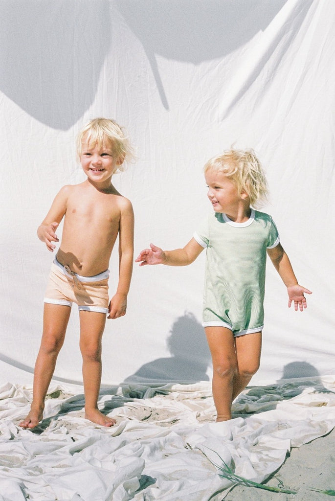 The US stockist of Zulu & Zephyr Mini Rib Onesie in Marine.  A loose fit gender neutral style made from sustainable ECONYL UPF 50+ fabric.  Short sleeved with contrasing back zipper and binds.  Fully lined.