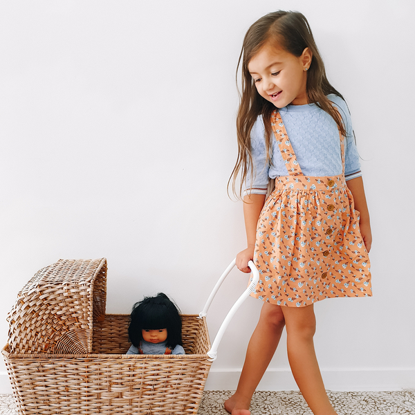 US stockist of Lacey Lane's Peach suspender skirt.  Peach cotton fabric with a pretty design of white and blue flowers.  Features pockets and oversized buttons down front.