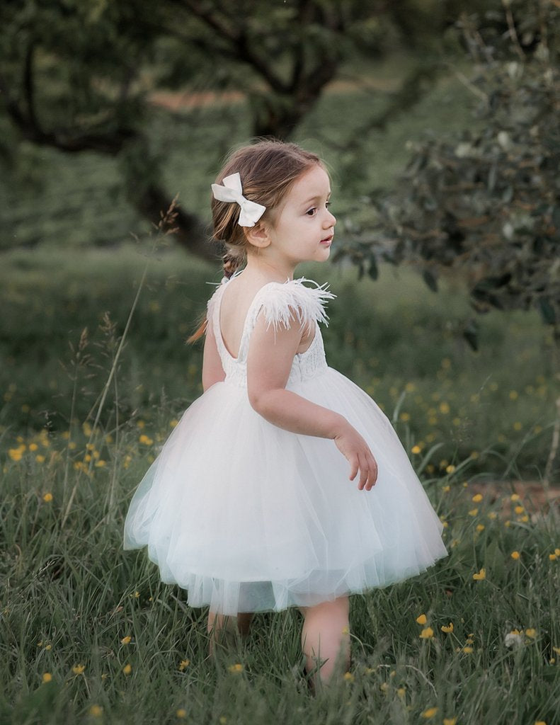 US stockist of Karibou Kids white Angelina Feather and Lace Dress.  Features 5 layer full skirt, lace bodice, scoop back and ostrich feather flutter sleeves. 