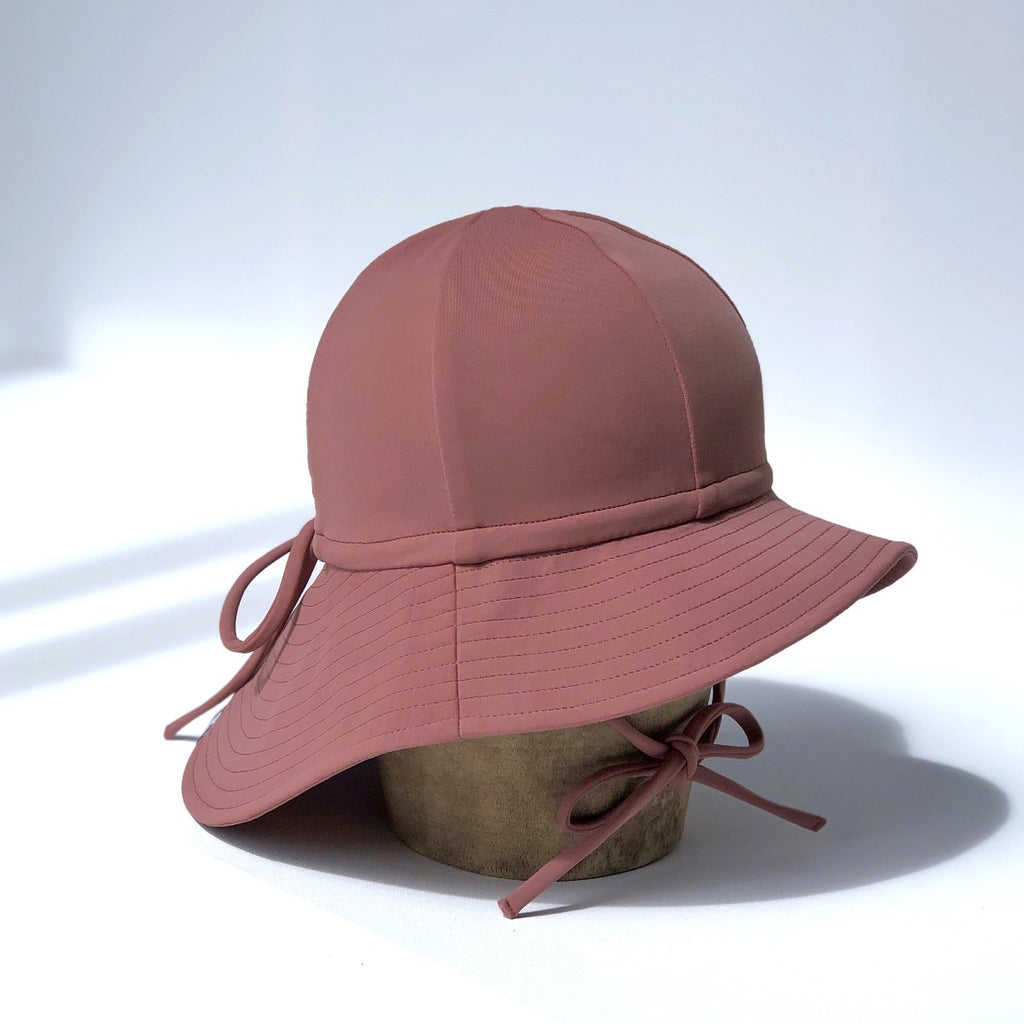 US stockist of Fini the Label's gender neutral, floppy swim hat in marsala. Features elongated back for added sun protection, chin strap and adjustable bow around crown for better fit. Brim is medium stiffness and can be flipped up at front.  Made from nylon/spandex and is quick drying.