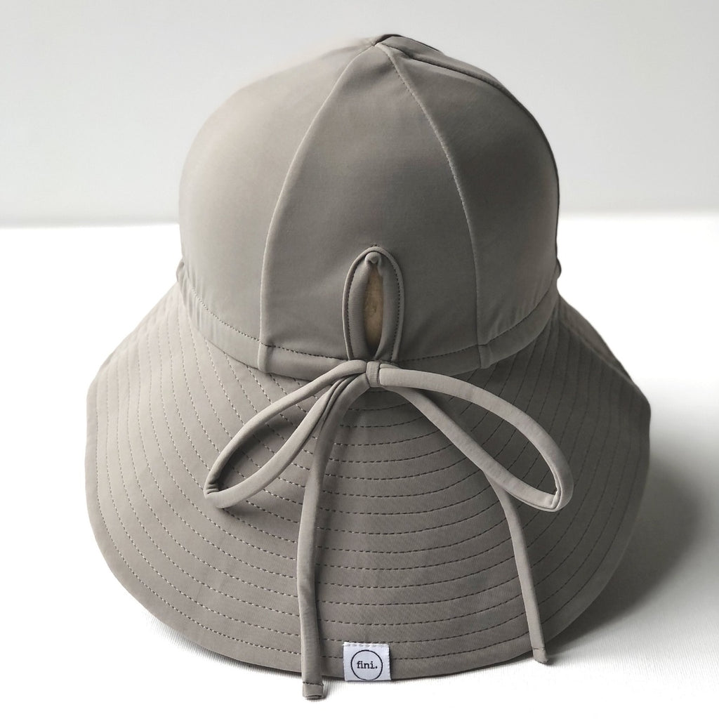 US stockist of Fini the Label's gender neutral, floppy swim hat in mushroom. Features elongated back for added sun protection, chin strap and adjustable bow around crown for better fit. Brim is medium stiffness and can be flipped up at front.  Made from nylon/spandex and is quick drying.
