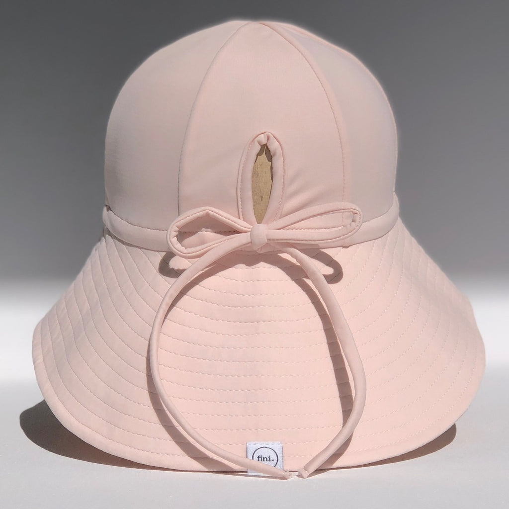 US stockist of Fini the Label's floppy swim hat in pale pink. Features elongated back for added sun protection, chin strap and adjustable bow around crown for better fit. Brim is medium stiffness and can be flipped up at front.  Made from nylon/spandex and is quick drying.