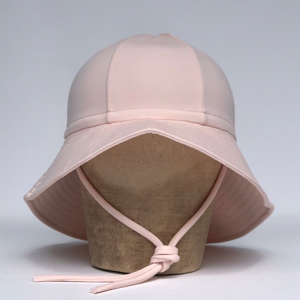 US stockist of Fini the Label's floppy swim hat in pale pink. Features elongated back for added sun protection, chin strap and adjustable bow around crown for better fit. Brim is medium stiffness and can be flipped up at front.  Made from nylon/spandex and is quick drying.