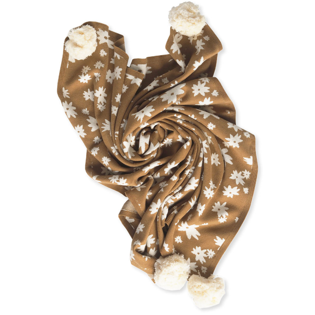 US stockist of Grown Clothing's gender neutral, organic cotton Winter Wonder Pom Pom Baby Blanket in bronze.  Made from organic cotton, with contrasting white jacquard flowers and white pom poms on each corner.