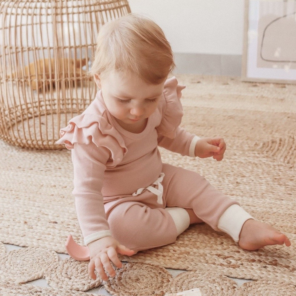 US stockist of India + Grace The Label's dusty pink long sleeved ribbed cotton bodysuit.  Features crotch snaps and beautiful ruffles at shoulder.  