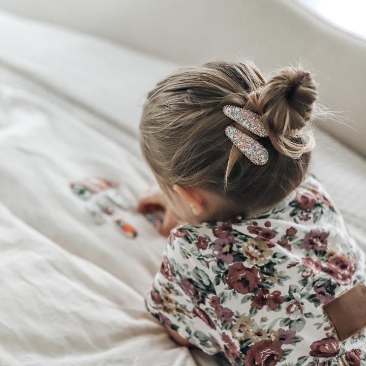 US stockist of Josie Joan's Lillia set of two fabric hair clips.  Cream colored fabric with pastel flowers in hues of pink, purple, blue and with green foilage. Features scalloped edges.