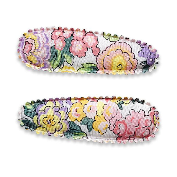 US stockist of Josie Joan's Little Audrey fabric baby hair clips.  Set of two fabric hair clips made from pale coloured fabric with bright orange, purple, red, yellow or pink flowers and  contrasting green leaves.  Has scalloped edging.