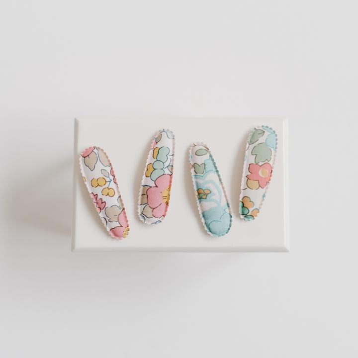 US stockist of Josie Joan's Little Kylie set of two fabric baby hair clips.  Cream colored fabric with blue, green flowers and red, yellow berries. Features scalloped edges.