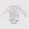 US stockist of Two Darlings gender neutral Milk stretch rib cotton bodysuit. Long Sleeves with 4 non functional wooden buttons kimono style across the front.