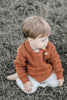 US stockist of Two Darlings gender neutral rust knit sweater.  Made from 100% cotton with two wood like buttons on the left shoulder.  Soft and stretchy.