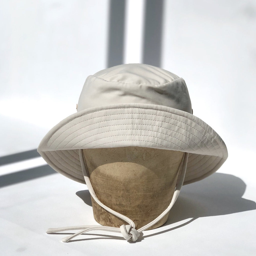 US stockist of Fini the Label's gender neutral, sailor swim hat in cream. Features elongated back for added sun protection, wide brim and chin strap. Brim is medium stiffness and can be flipped up at front. Sides can be worn buttoned up for that sailor look.  Made from nylon/spandex and is quick drying.
