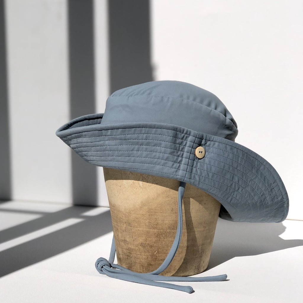 US stockist of Fini the Label's gender neutral, sailor swim hat in heaven. Features elongated back for added sun protection, wide brim and chin strap. Brim is medium stiffness and can be flipped up at front. Sides can be worn buttoned up for that sailor look.  Made from nylon/spandex and is quick drying.
