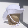 US stockist of Fini the Label's gender neutral, sailor swim hat in white. Features elongated back for added sun protection, wide brim and chin strap. Brim is medium stiffness and can be flipped up at front. Sides can be worn buttoned up for that sailor look.  Made from nylon/spandex and is quick drying.