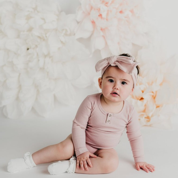 US stockist of Karibou Kids soft pink Willow long sleeve henley bodysuit in ribbed cotton blend.