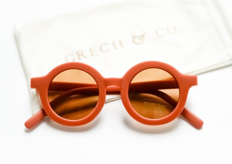 US stockist of Grech & Co's gender neutral sustainable sunglasses.  Made from recycled plastic, with round amber lens with UV 400 protection in a rust color.