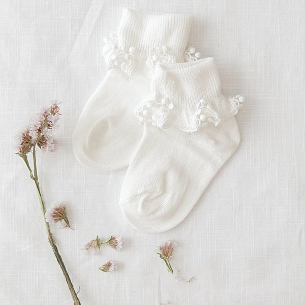 US stockist of Karibou Kid's white ankle pom pom ruffle socks.  Made from a cotton blend.