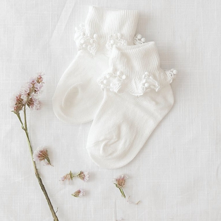 US stockist of Karibou Kid's white ankle pom pom ruffle socks.  Made from a cotton blend.