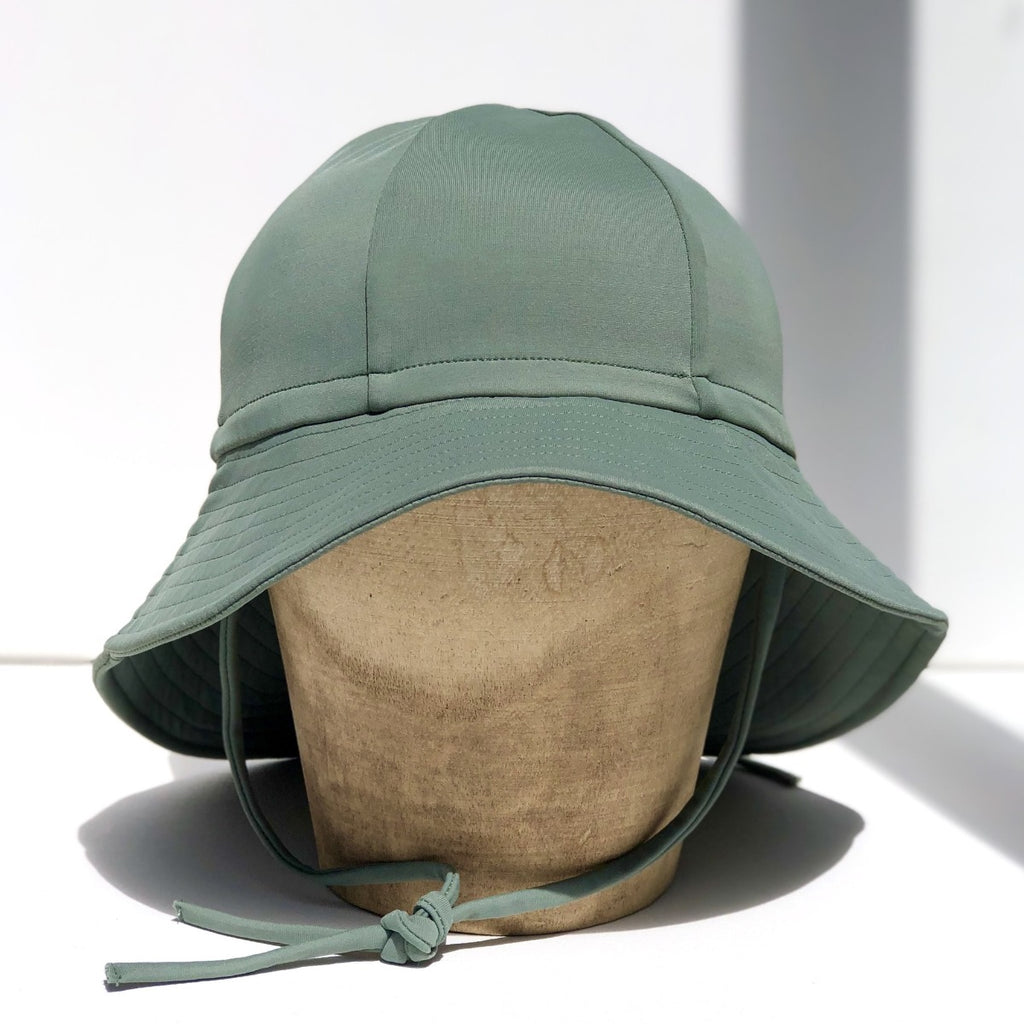 US stockist of Fini the Label's gender neutral, floppy swim hat in Ivy Green. Features elongated back for added sun protection, chin strap and adjustable bow around crown for better fit. Brim is medium stiffness and can be flipped up at front.  Made from nylon/spandex and is quick drying.