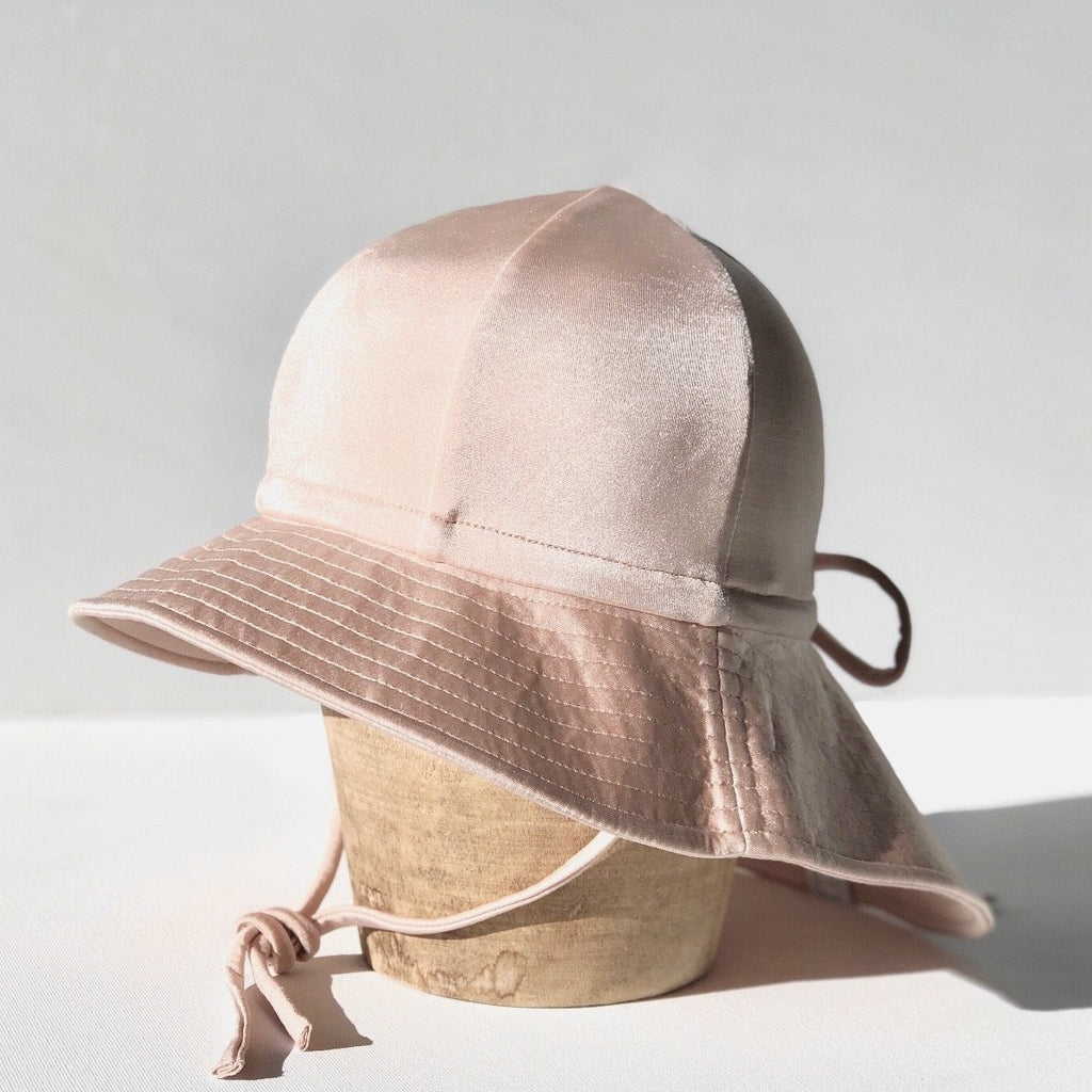 US stockist of Fini the Label's gender neutral, floppy swim hat in Shimmer Champagne. Features elongated back for added sun protection, chin strap and adjustable bow around crown for better fit. Brim is medium stiffness and can be flipped up at front.  Made from nylon/spandex and is quick drying.
