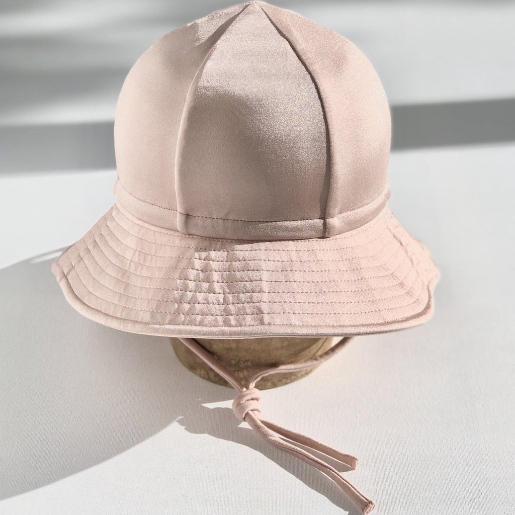 US stockist of Fini the Label's gender neutral, floppy swim hat in Shimmer Champagne. Features elongated back for added sun protection, chin strap and adjustable bow around crown for better fit. Brim is medium stiffness and can be flipped up at front.  Made from nylon/spandex and is quick drying.