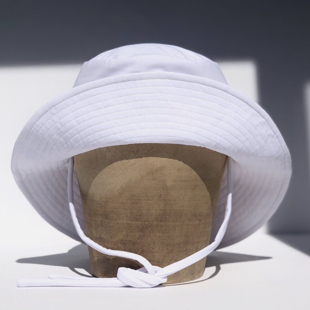US stockist of Fini the Label's gender neutral, sailor swim hat in white. Features elongated back for added sun protection, wide brim and chin strap. Brim is medium stiffness and can be flipped up at front. Sides can be worn buttoned up for that sailor look.  Made from nylon/spandex and is quick drying.