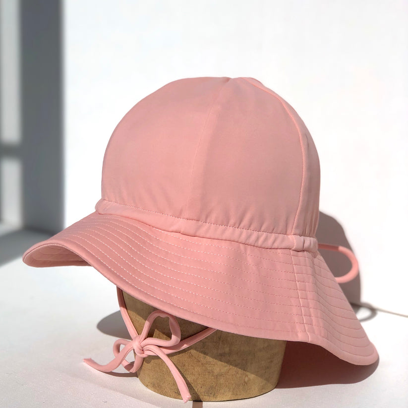 US stockist of Fini the Label's floppy swim hat in pink. Features elongated back for added sun protection, chin strap and adjustable bow around crown for better fit. Brim is medium stiffness and can be flipped up at front.  Made from nylon/spandex and is quick drying.