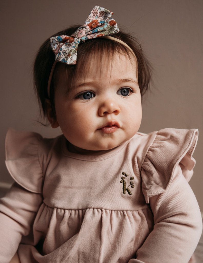 US stockist of Karibou Kid's Milana Winged Playsuit in soft pink.  Made from soft cotton, featuring long sleeves and ruffled wings at shoulders.