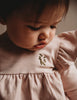 US stockist of Karibou Kid's Milana Winged Playsuit in soft pink.  Made from soft cotton, featuring long sleeves and ruffled wings at shoulders.
